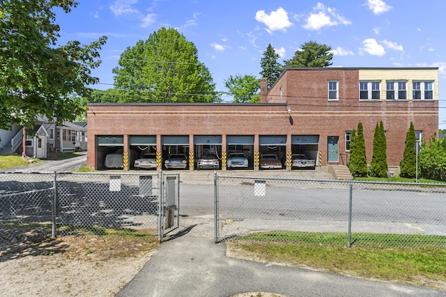 exterior space featuring brick siding, a gate, uncovered parking, and fence