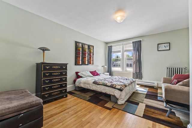 bedroom with baseboards, baseboard heating, radiator heating unit, and wood-type flooring