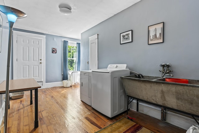 laundry area with baseboards, laundry area, washer and clothes dryer, and hardwood / wood-style flooring