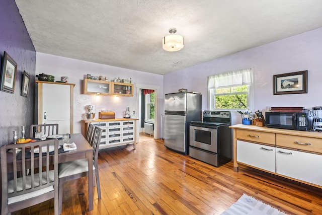 kitchen featuring glass insert cabinets, a wealth of natural light, light wood-style flooring, and appliances with stainless steel finishes
