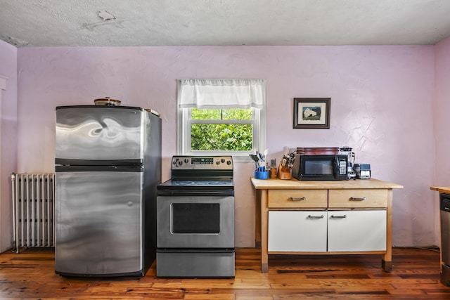 kitchen with light countertops, radiator, stainless steel appliances, and wood finished floors