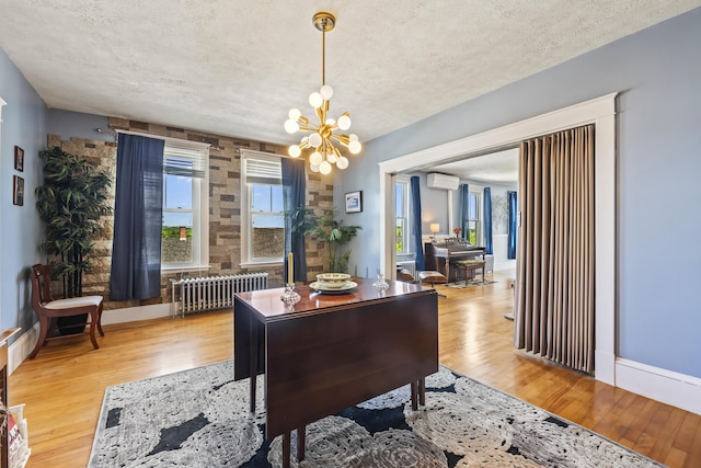 office space with a textured ceiling, baseboards, light wood-type flooring, radiator, and an inviting chandelier