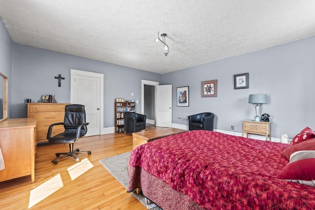 bedroom featuring a textured ceiling, baseboards, and wood finished floors