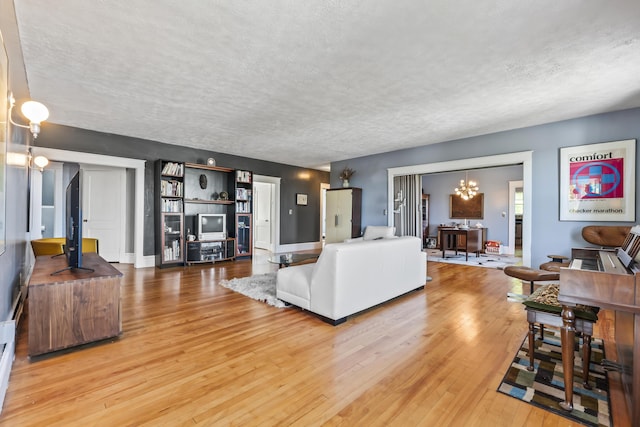 living area with baseboards, light wood-style floors, a chandelier, and a textured ceiling