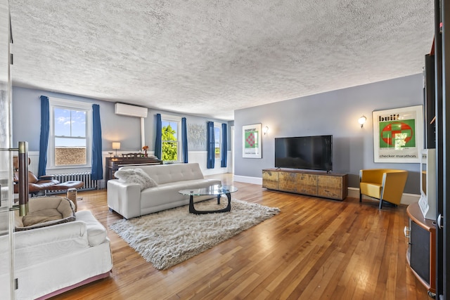 living area featuring a wealth of natural light, radiator heating unit, an AC wall unit, and hardwood / wood-style flooring