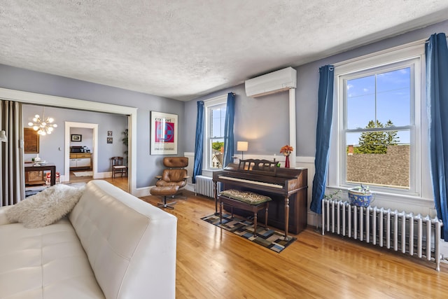 living area featuring a wall mounted AC, wood finished floors, radiator heating unit, and an inviting chandelier