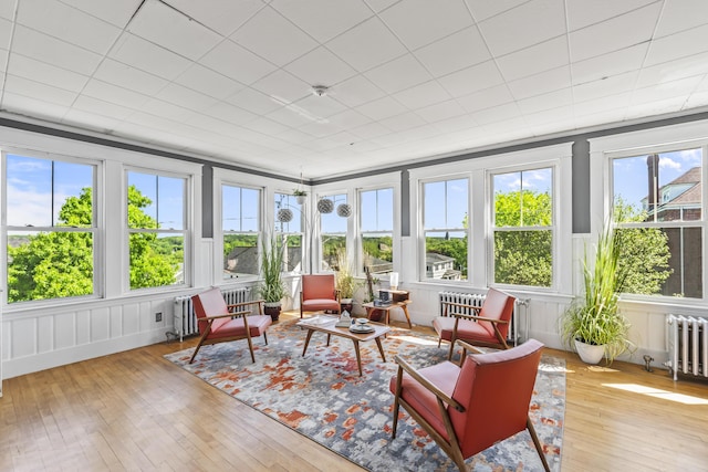 sunroom featuring radiator, a wooden deck, a decorative wall, and hardwood / wood-style floors