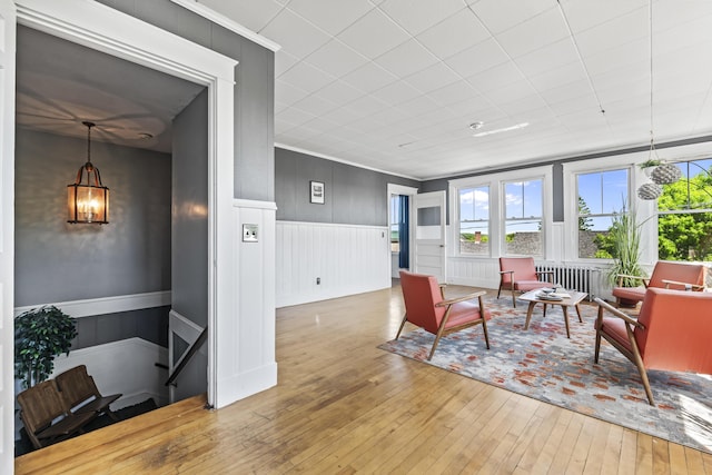 living room featuring hardwood / wood-style floors, a wainscoted wall, and ornamental molding
