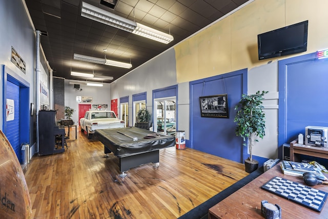 recreation room with pool table, a towering ceiling, and wood-type flooring