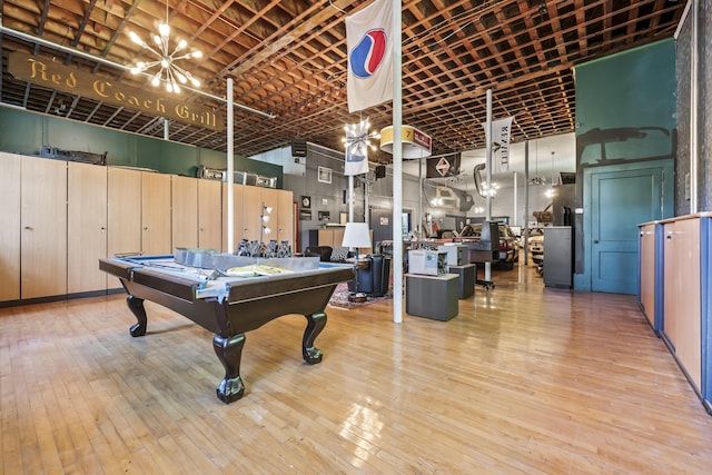 rec room featuring a high ceiling, hardwood / wood-style flooring, pool table, and a chandelier