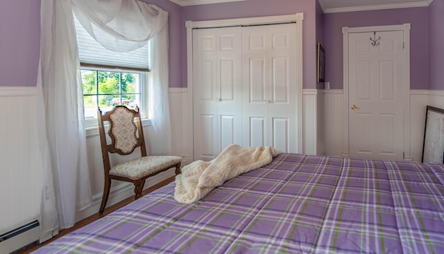 bedroom with a baseboard heating unit, a closet, and crown molding