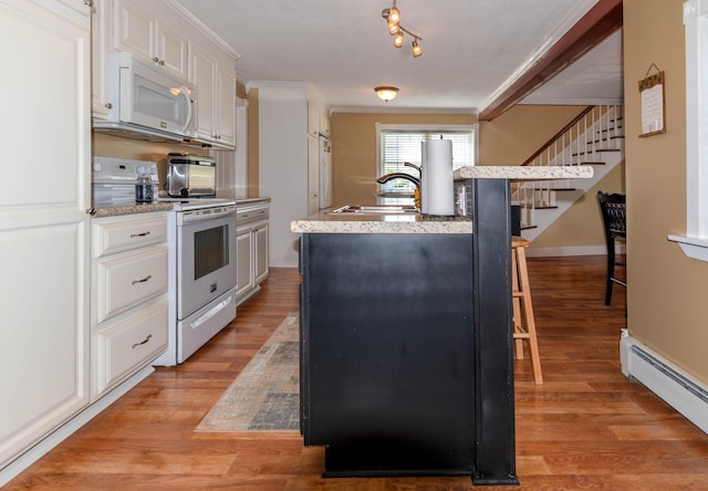 kitchen featuring an island with sink, white appliances, baseboard heating, ornamental molding, and sink