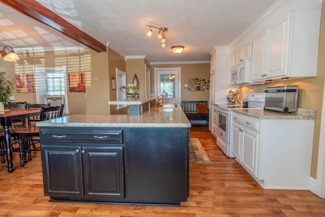 kitchen with white cabinetry, white appliances, and a kitchen island with sink