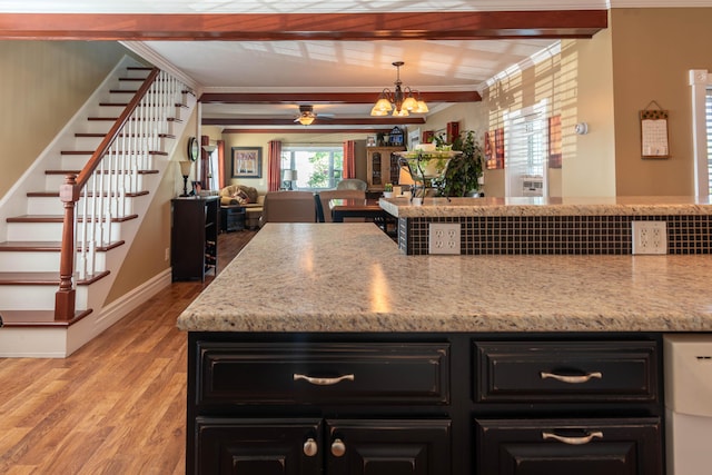 kitchen with pendant lighting, beamed ceiling, light hardwood / wood-style floors, a chandelier, and light stone counters