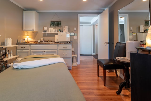 bedroom featuring light wood-type flooring, crown molding, and sink