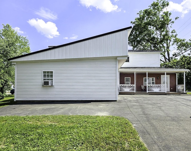 view of side of property featuring covered porch, cooling unit, and a lawn