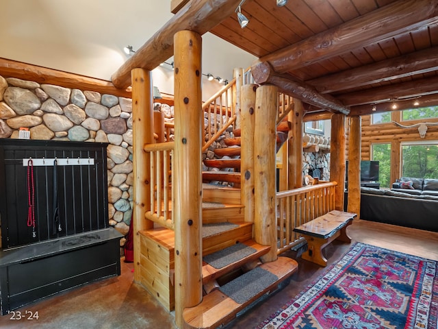 stairway with beam ceiling, rustic walls, wooden ceiling, and track lighting