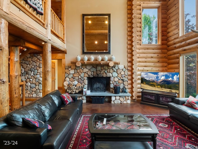 living room with rustic walls, a fireplace, a healthy amount of sunlight, and a high ceiling