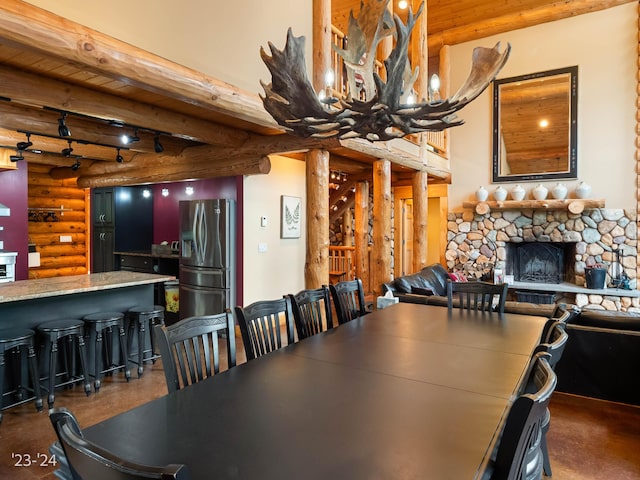 dining area with beam ceiling, log walls, wooden ceiling, a notable chandelier, and a fireplace