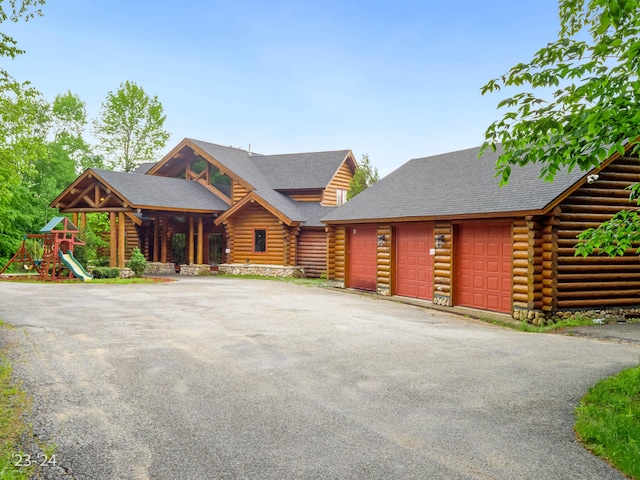 log-style house featuring a playground and a garage