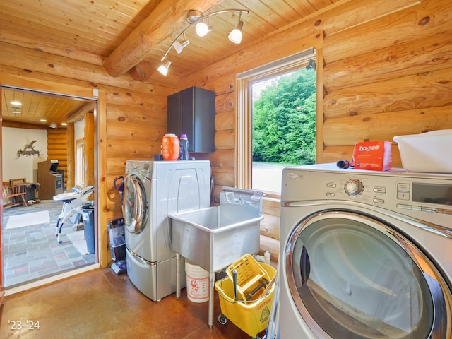 laundry room featuring washing machine and clothes dryer, rustic walls, sink, and wood ceiling