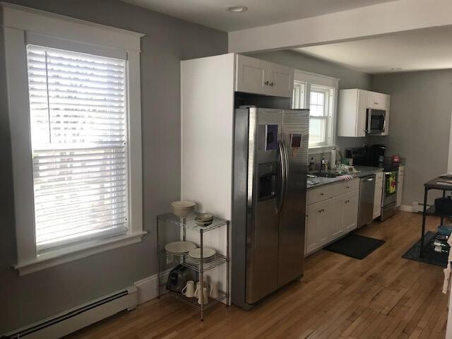 kitchen featuring a baseboard heating unit, dark wood-type flooring, stainless steel appliances, and white cabinetry