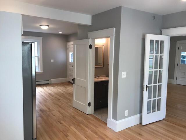 corridor with a baseboard heating unit, light wood-type flooring, and sink