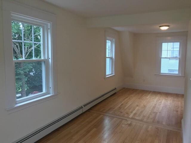 spare room with baseboard heating and wood-type flooring