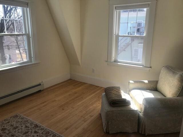 sitting room featuring baseboard heating, plenty of natural light, and hardwood / wood-style floors