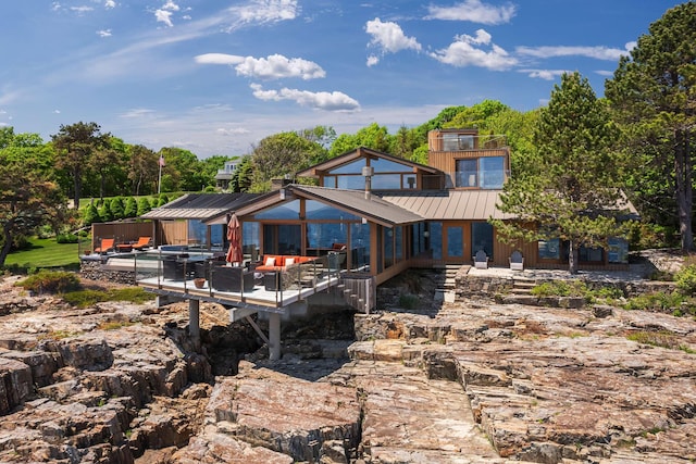 back of property with an outdoor living space and a jacuzzi
