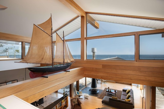interior space with a water view, high vaulted ceiling, hardwood / wood-style floors, and beamed ceiling