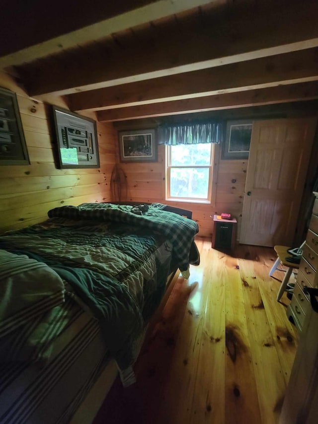 bedroom featuring wood-type flooring, wood walls, and beamed ceiling