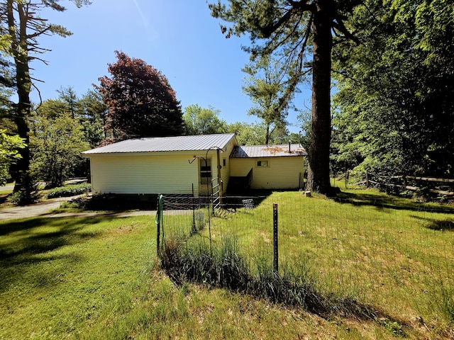 view of front facade with metal roof and a front lawn