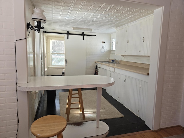 kitchen with brick wall, a barn door, a sink, and an ornate ceiling