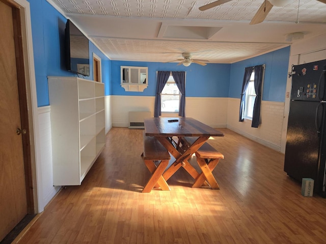 dining area featuring ceiling fan, wood finished floors, and wainscoting