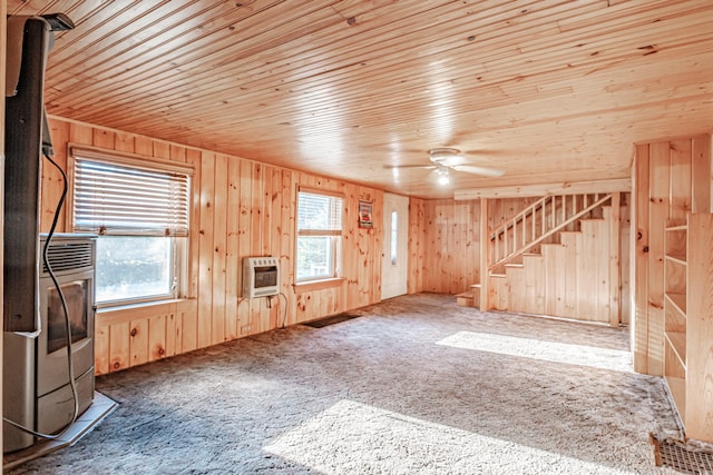 unfurnished living room with carpet, ceiling fan, plenty of natural light, and wood walls