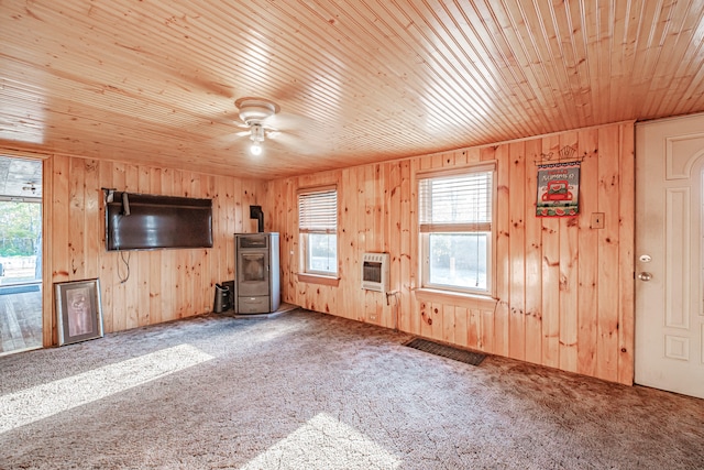 unfurnished living room featuring wooden walls, carpet floors, wooden ceiling, and ceiling fan