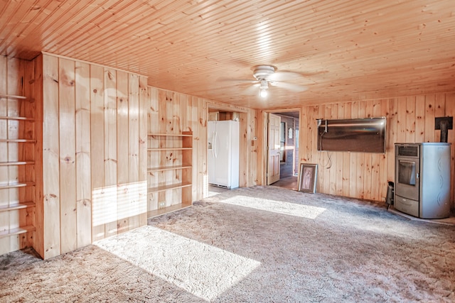 unfurnished living room with ceiling fan, carpet floors, wooden walls, and wooden ceiling