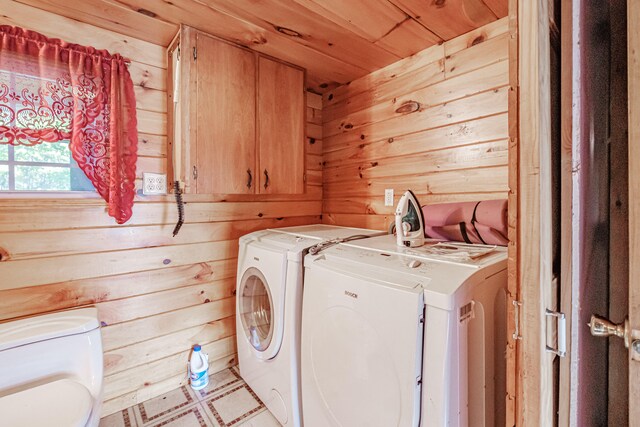 clothes washing area featuring washer and dryer, wood ceiling, and wooden walls