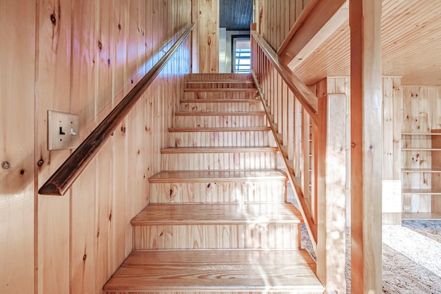 staircase featuring wood walls