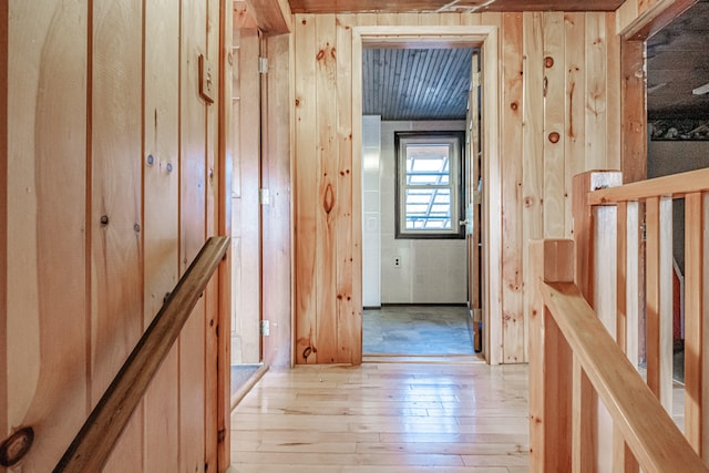 hallway with light hardwood / wood-style flooring and wooden walls