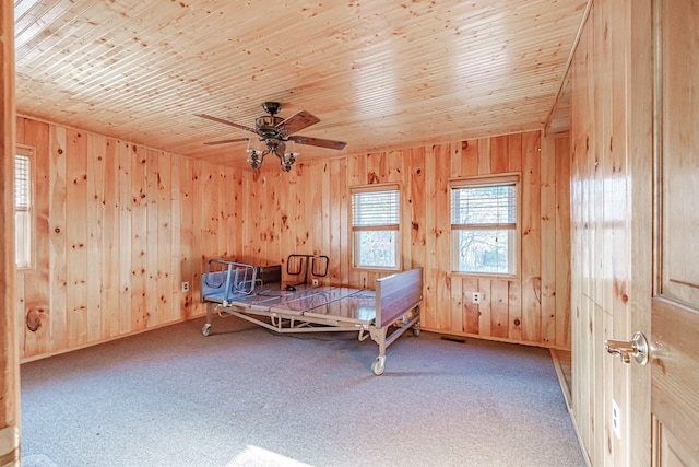 carpeted bedroom with wooden ceiling, ceiling fan, and wooden walls