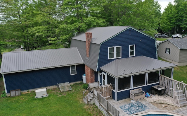 back of property featuring a wooden deck, a yard, and a sunroom