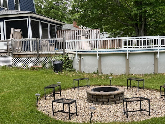 view of yard with a pool side deck, a fire pit, and a sunroom