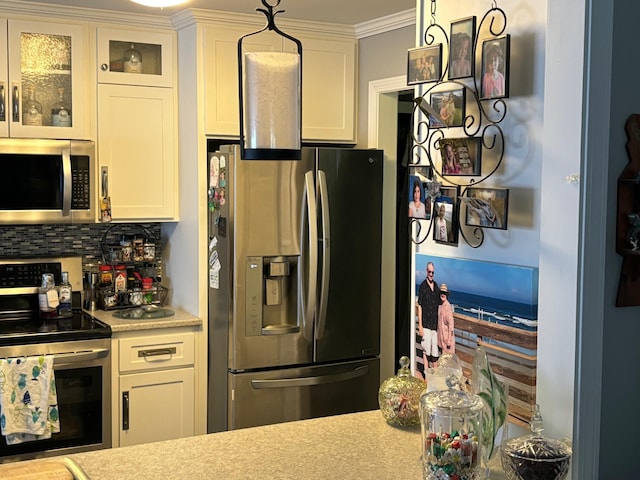 kitchen with tasteful backsplash, hanging light fixtures, white cabinets, and appliances with stainless steel finishes