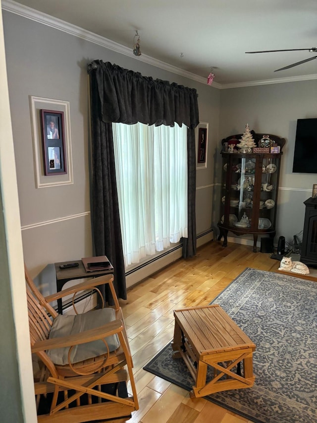 living room with a baseboard heating unit, crown molding, a wood stove, and light hardwood / wood-style flooring