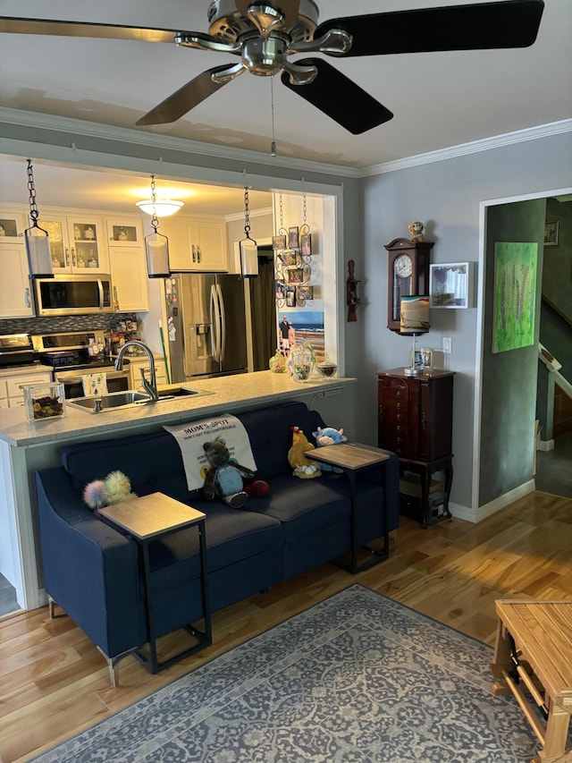 living room with hardwood / wood-style flooring, ceiling fan, crown molding, and sink