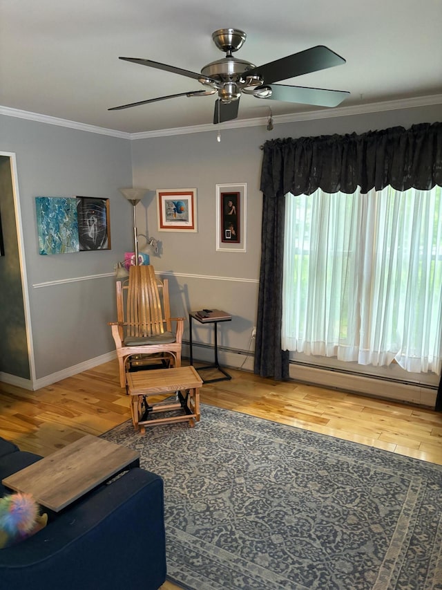 sitting room with baseboard heating, wood-type flooring, and crown molding