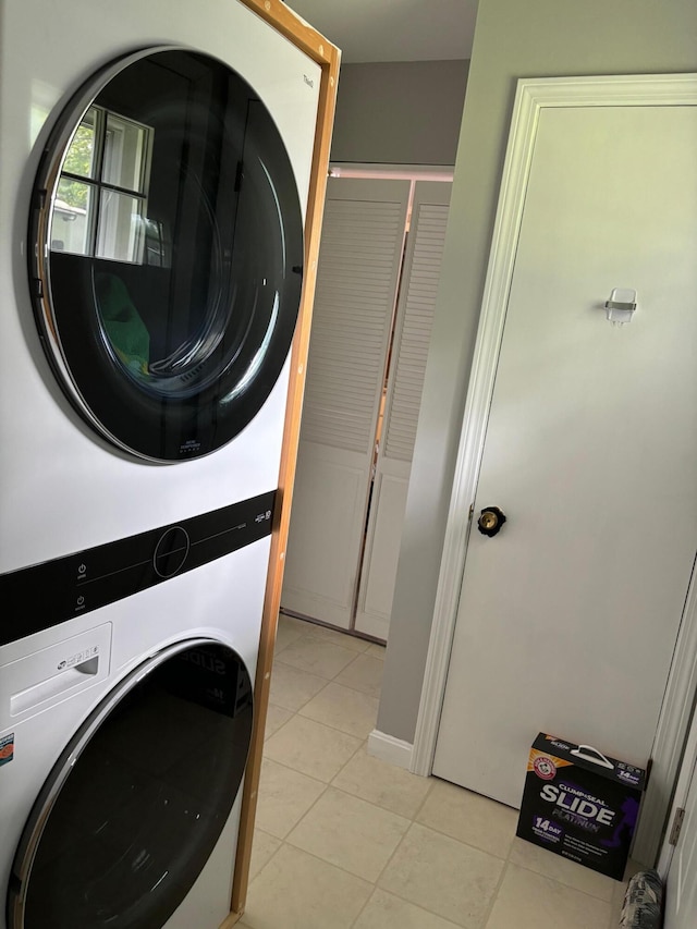 laundry room with stacked washing maching and dryer and light tile patterned floors