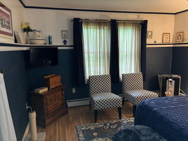 bedroom featuring crown molding, a baseboard heating unit, and hardwood / wood-style flooring